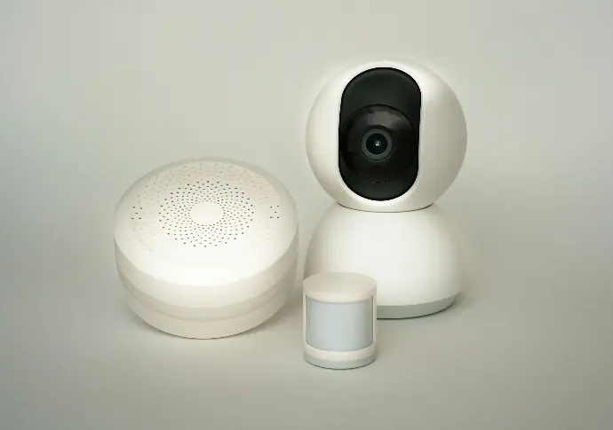 A white camera sitting next to a white container